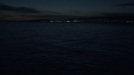 blue water in low light with distant seaside town