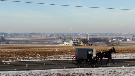 Antenne-Neben-Einem-Amischen-Buggy,-Der-Im-Winterschnee-Von-Einem-Pferd-Gezogen-Wird