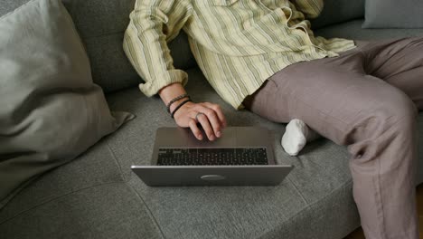 person relaxing on couch using laptop