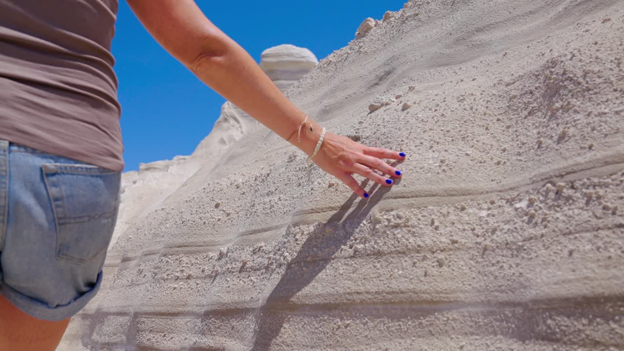 그리스 미로스의 이 많은 날에 하 바위 지층을 보여주는 여성의 손이 미끄러지는 느린 움직임 클로즈업