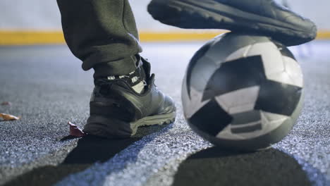 primer plano del pie derecho de un jugador de fútbol rodando suavemente una pelota de fútbol en césped artificial, superficie del suelo texturizada, movimiento dinámico, fondo bordeado de amarillo