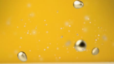 Animation-Von-Vier-Fallenden-Schokoladengoldenen-Ostereiern-Und-Fliegenden-Konfetti-Auf-Gelbem-Hintergrund