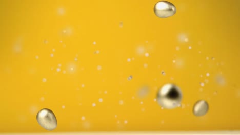 animation of four chocolate golden easter eggs falling and confetti flying on yellow background