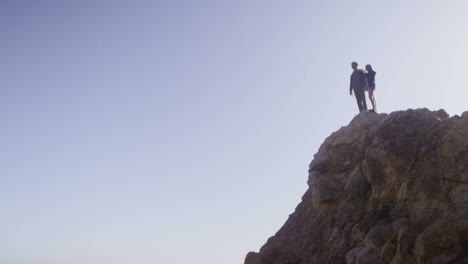 wide view of a couple standing atop a sea cliff