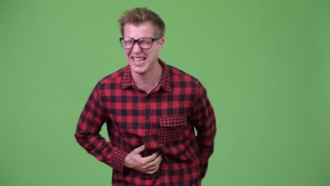 young handsome nerd man having stomach ache