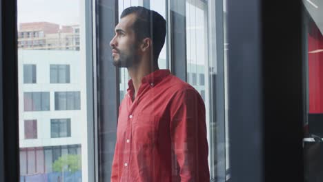 Portrait-of-mixed-race-businessman-looking-through-the-window