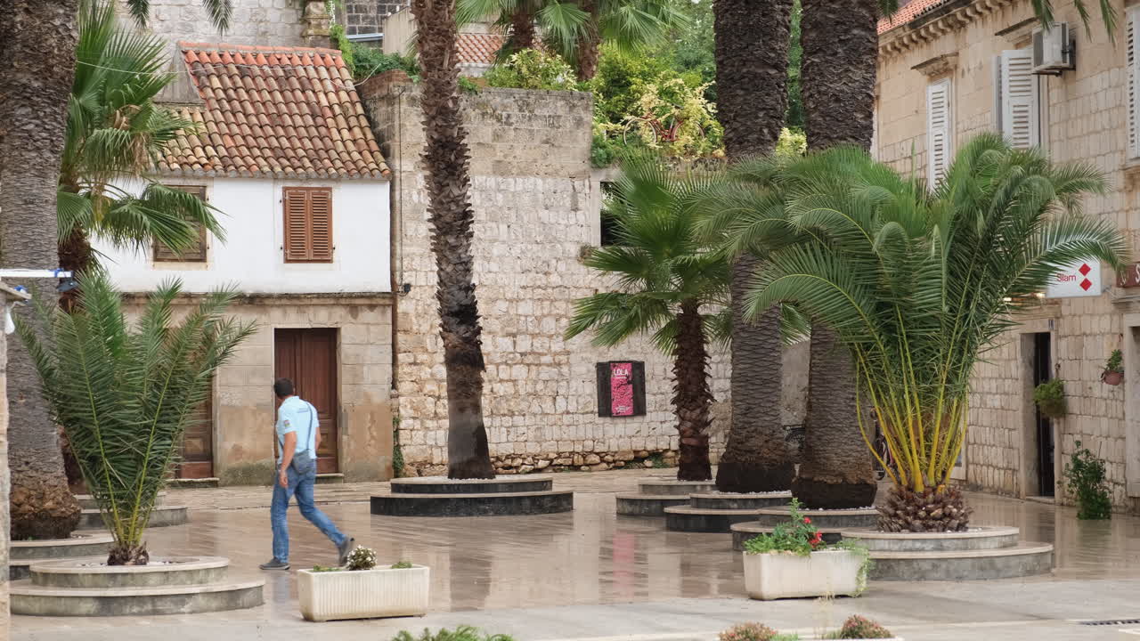 Adult Man Walking At Town Square With Historic Buildings In Vis Island, Croatia. - wide shot