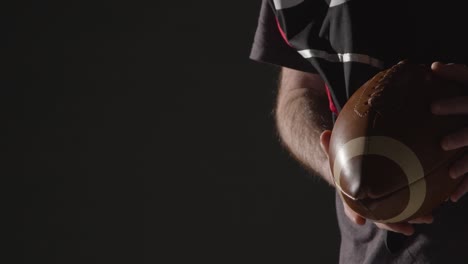 Close-Up-Studio-Shot-Of-American-Football-Player-Holding-Ball-With-Low-Key-Lighting-1