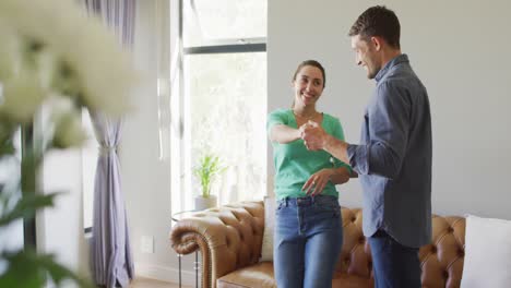 Una-Joven-Pareja-Caucásica-Feliz-Enamorada-Hablando-Y-Bailando-En-Casa