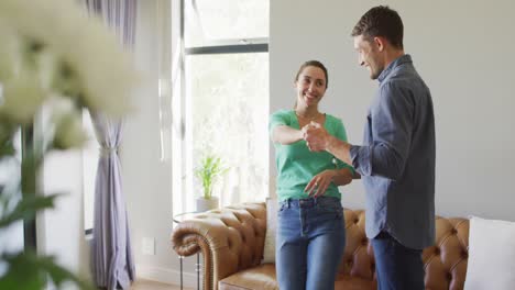 una joven y feliz pareja caucásica enamorada hablando y bailando en casa