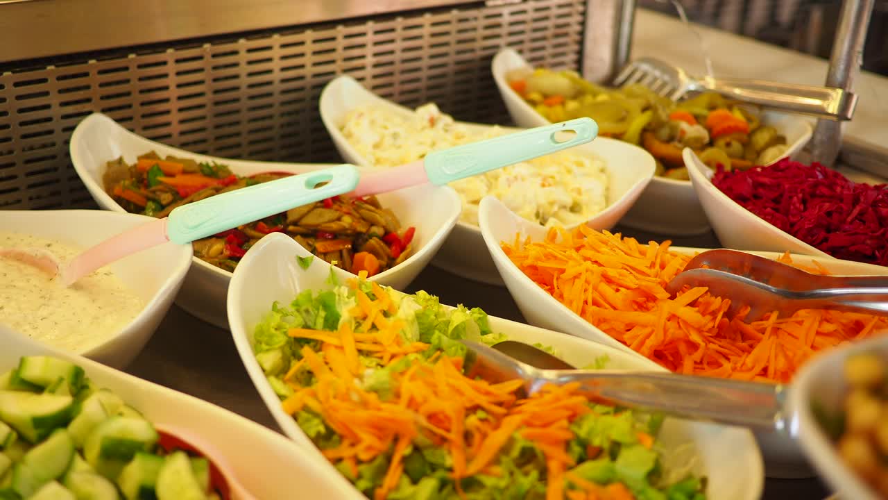 Mano che serve insalate fresche e verdure da un buffet