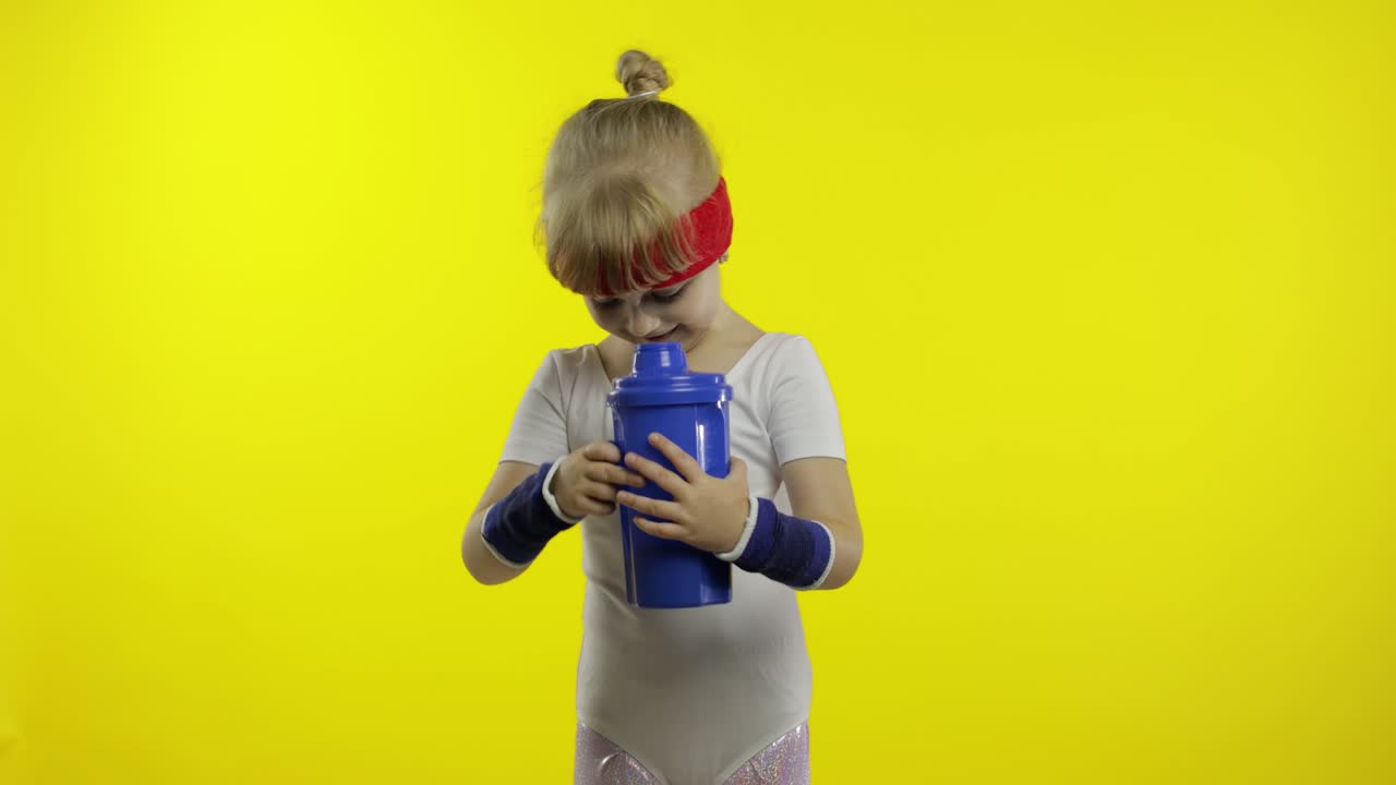 niña con ropa deportiva bebiendo agua para refrescarse después de los ejercicios de fitness. niño pequeño atlético
