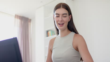 Caucasian-young-woman-standing,-looking-at-laptop,-smiling