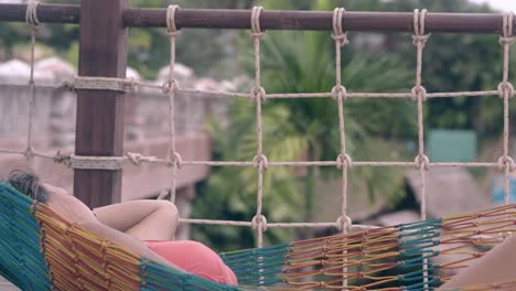 slim girl in swimsuit lies in striped hammock and sleeps