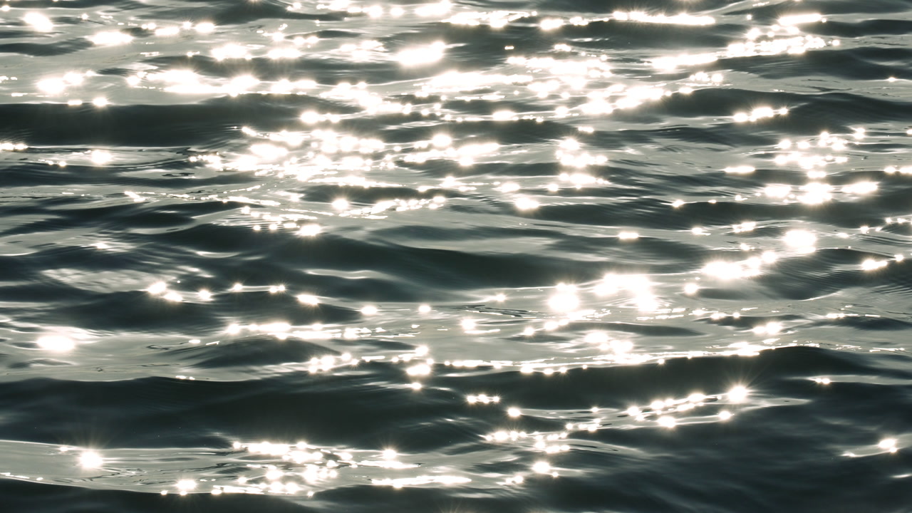 Intense sun glitter on bright blue sea water ripples.
