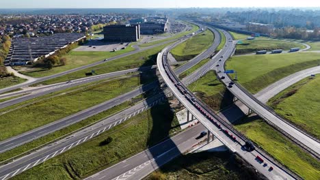 cars driving on a1 and a5 highway interchange near residential area in kaunas, lithuania, during sunny autumn day with long shadows from bridge, aerial view