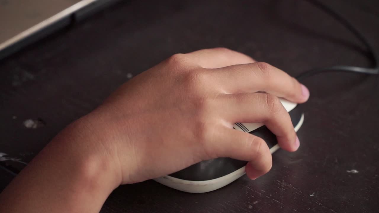 Child hand navigating computer mouse. Home learning, digital skills, and education technology