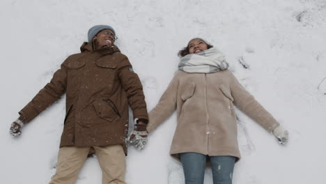 couple making snow angels in the snow