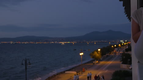 En-La-Costa-De-La-Ciudad-De-Perea,-Grecia,-En-Las-Calles-Nocturnas,-Gente-Caminando.