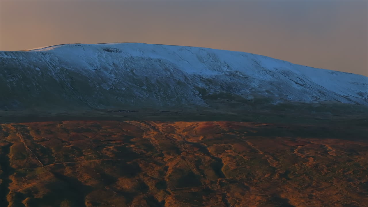 lente larga de primer plano toma aérea de un dron de la nevada montaña whernside al atardecer hora de oro yorkshire dales reino unido