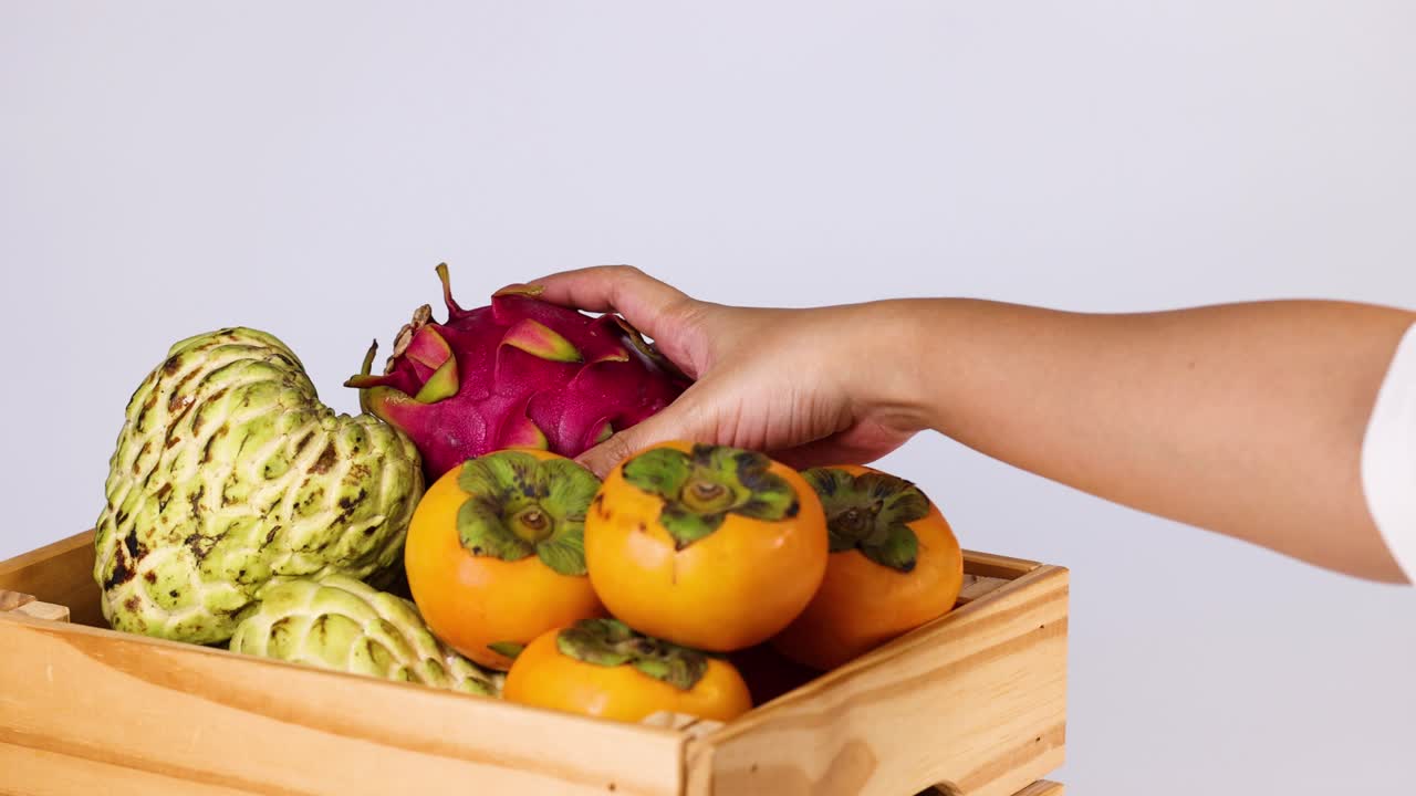 arreglando frutas a mano en una canasta de madera