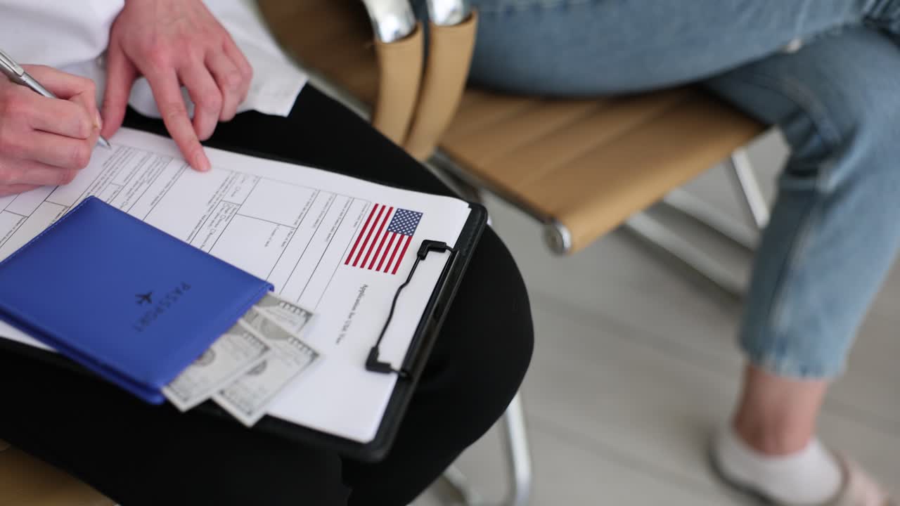 People fill in visa application form near dollar bills