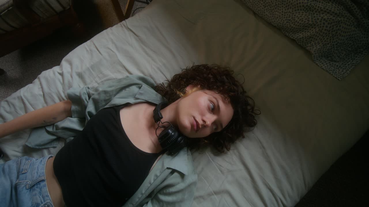 mujer acostada en una cama con auriculares