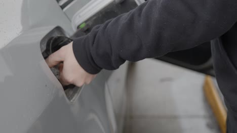 Gas-station-white-caucasian-man-with-wedding-ring-filling-up-silver-car-pressing-and-opening-fuel-tank-cover-and-grabbing-gas-cap