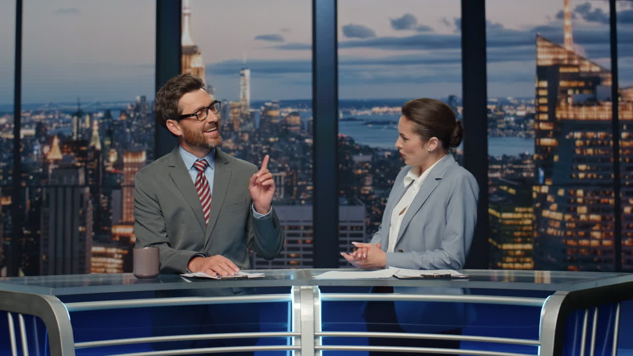 dos lectores de noticias discutiendo las noticias de la noche en un estudio de televisión.