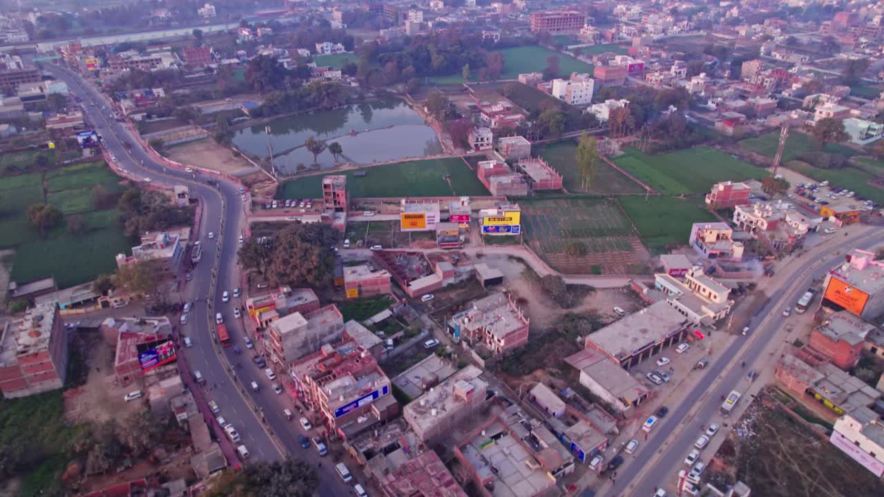Chudamadh circle with buildings and crop fields, day time, push in, tilt up, drone shot, 4k.