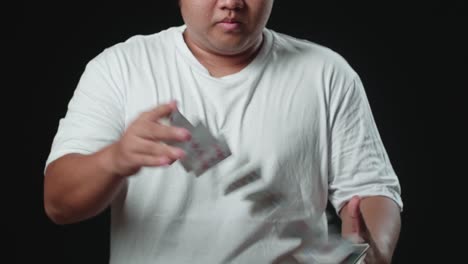 man showing card spring, cardistry on black background