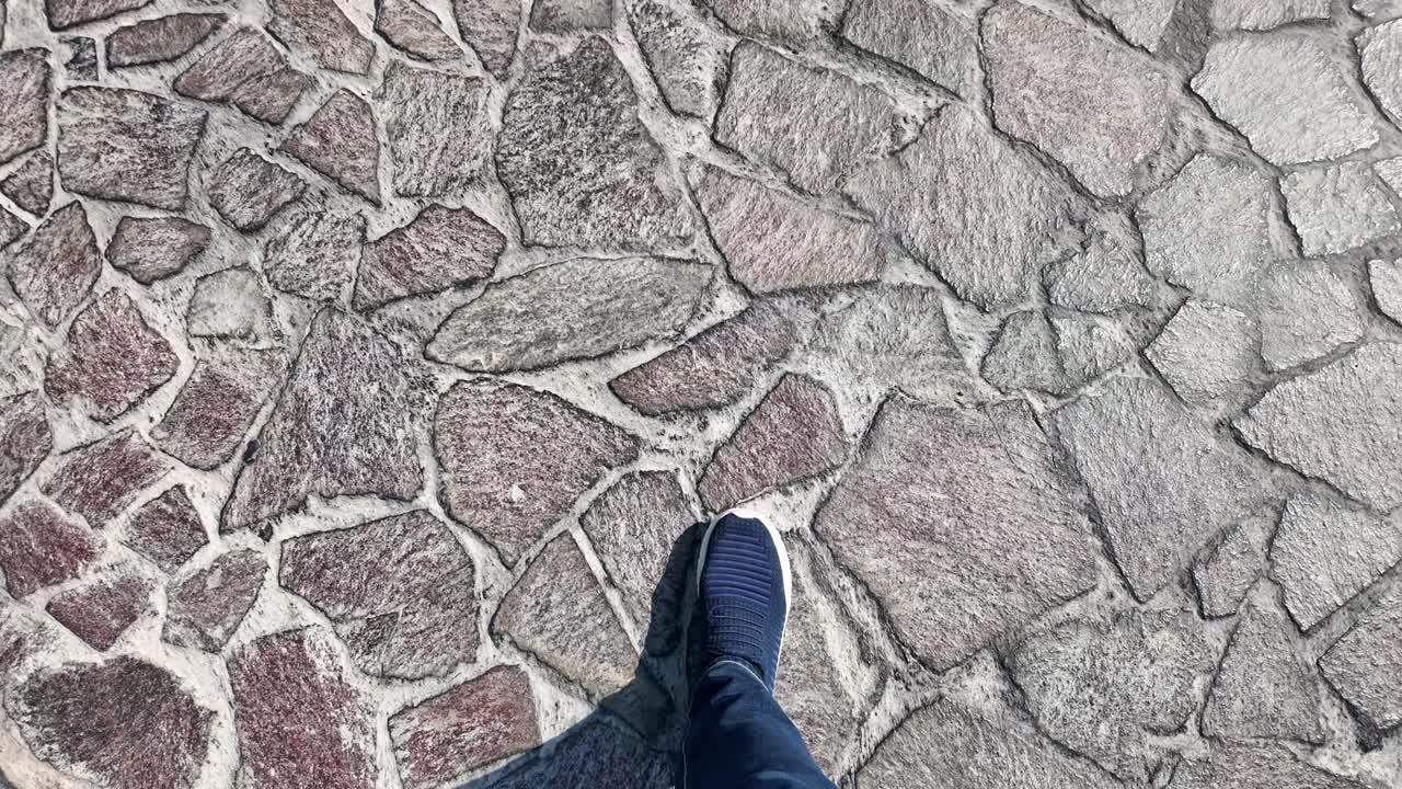 First Person View of Feet Walking on a Cobblestone Path