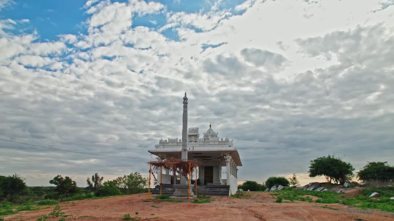 Hindu temple with flagstaff erected or Dhvajastambha and clouds, day time, low angle, semi orbit, drone shot, 4k.