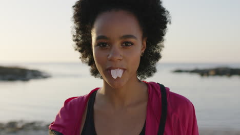 portrait of young african american woman blowing bubblegum cheerful laughing on sunny beach