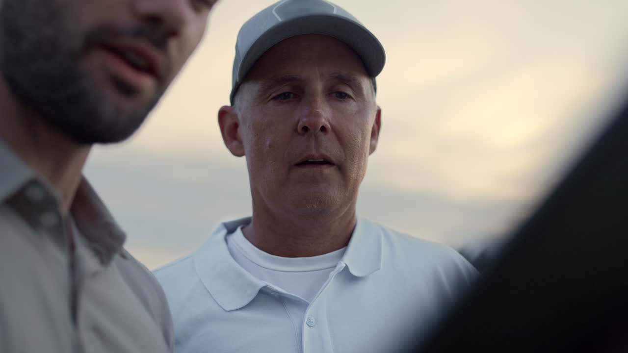 Padre e figlio in videochiamata su tablet durante il tempo libero sul campo da golf. Due uomini chiacchierano online all'aperto.