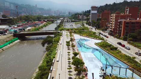 Slow-aerial-shot-of-park-and-busy-traffic-roads-of-Medellin,-Laureles-and-Pueblo-Paisa