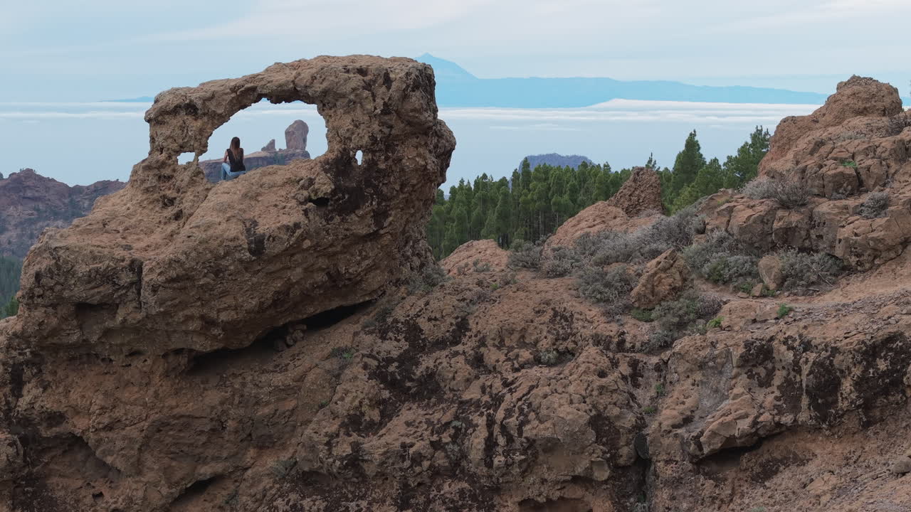 Gran Canaria:
Elegant aerial footage of a woman enjoying the dramatic scenery of the Window of Roque Nublo (Gañifa) and Mount Teide.