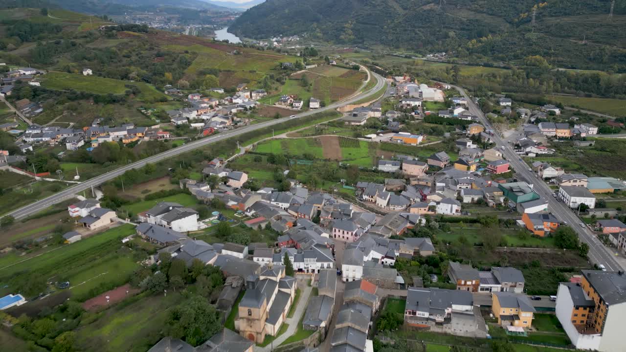 Dynamic drone view of A Rúa town, Galicia, with rolling hills and expansive sky in the background