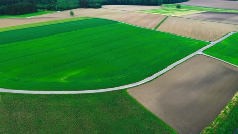 aerial-shot-of-plowed-farmland-and-green-fields,-4k