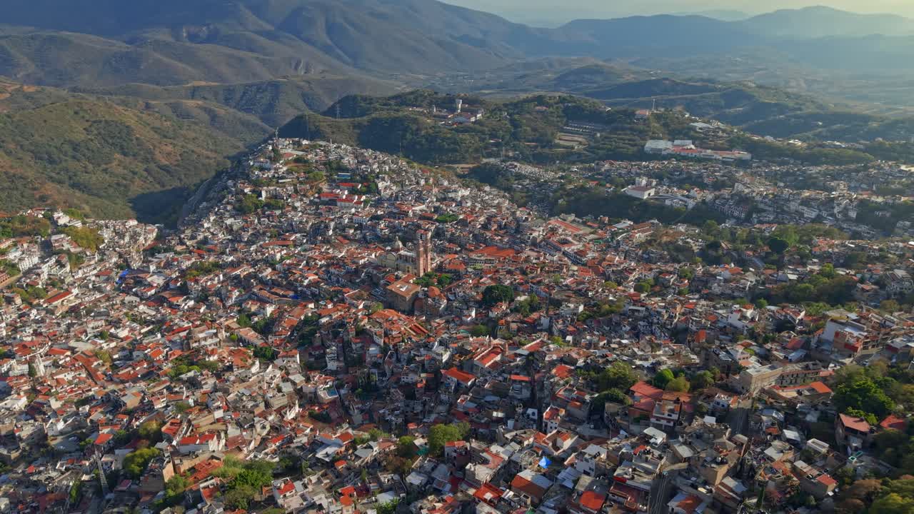 Ilmakuva Taxco de Alarcónista, Guerrerosta, Meksikosta aurinkoisena päivänä vuorten ollessa taustalla, siirtomaa-arkkitehtuuria valkoisine taloineen ja tiilikattoineen