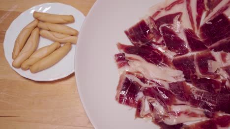 Jamón-Ibérico-En-Plato-Giratorio-Con-Palitos-De-Pan-Pico-Tradicionales-Españoles,-Arriba