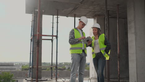 equipo de construcción o arquitecto y constructor o trabajador con cascos discuten un plan de construcción de andamios o un plan o una lista de comprobación