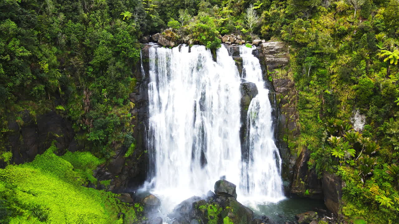 drone moviéndose hacia una cascada en un alto acantilado rocoso