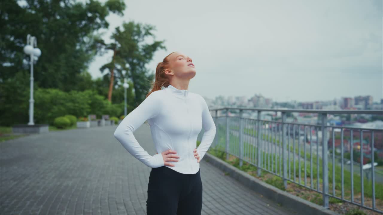 Redhead woman taking a deep breath after exercise in the park