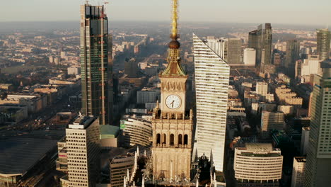 Absteigende-Luftaufnahmen-Der-Turmspitze-Mit-Turmuhr-Auf-Dem-Pkin-Hochhaus.-Moderne-Hochhäuser-Im-Hintergrund.-Warschau,-Polen