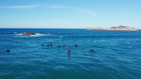 aerial shot of surfers waiting for waves during a sunny day at the beach in cantabria, spain