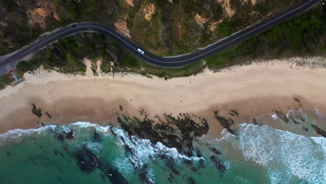 Cinematic-downward-angle-drone-shot-of-Wellington-Rocks-with-coastal-highway-and-ocean-waves-at-Nambucca-Heads-New-South-Wales-Australia