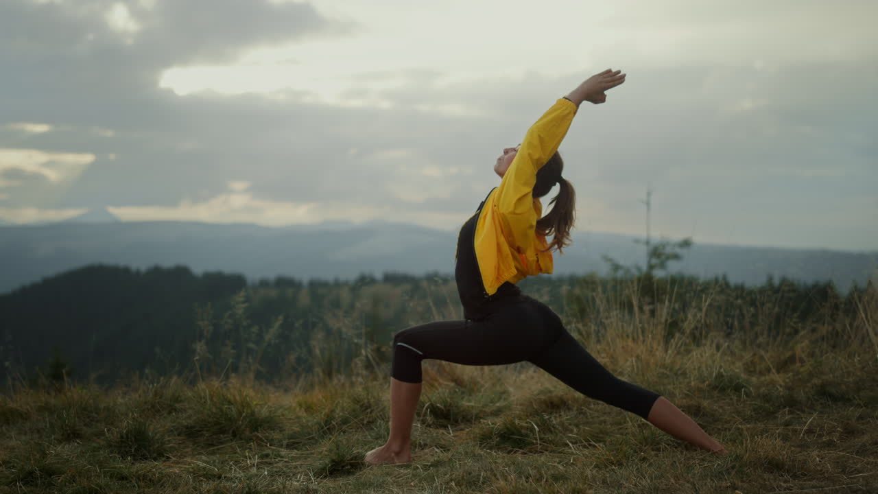 mujer de yoga de pie en la postura de guerrero. chica en forma meditando en las montañas