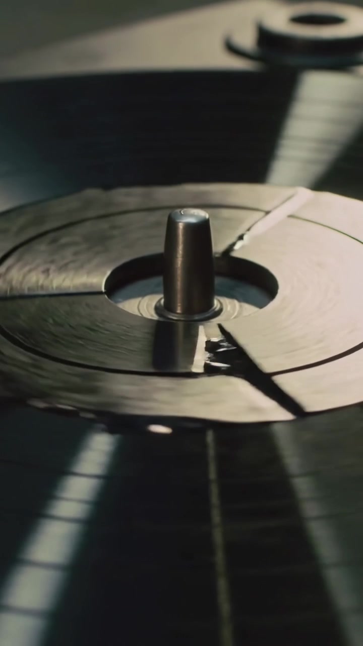 Video verticale: Perno che gira, disco incrinato che ruota sul piatto, residui che catturano la luce