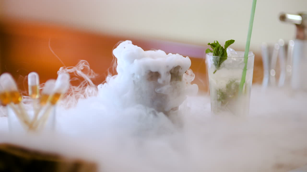 바텐더가 음료 1을 준비하는 동안 유리에 드라이 아이스